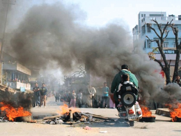 A man tries to negotiate his scooter through a row of burning tyres at Keishamthong area while taking his kids for tuition during the bandh called to press the demand for arresting NSCN (IM) cadre who molested and assaulted film actress Momoco