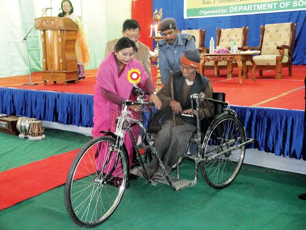 Social Welfare Minister AK Mirabai handing over a tri-cycle to a disabled person during the observance of International Day for PWDs at Khuman Lampak