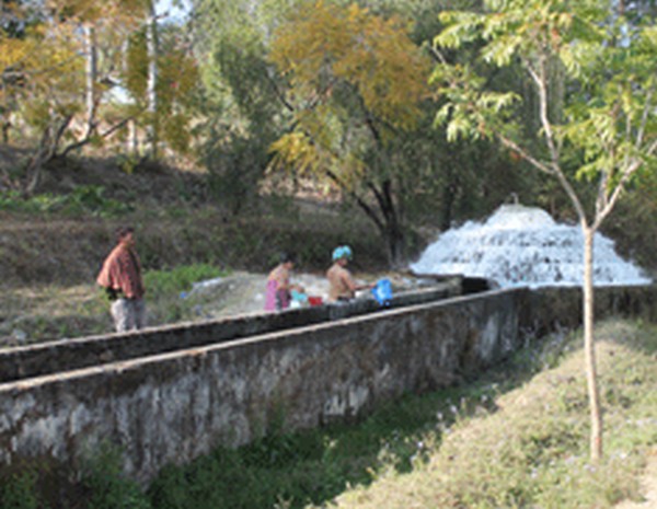 People washing clothes/bathing near a water treatment plant