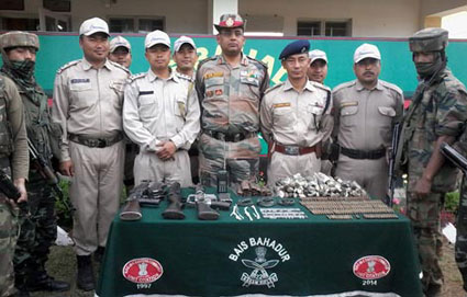 Police and para-military men pose with the seized arms and ammo.