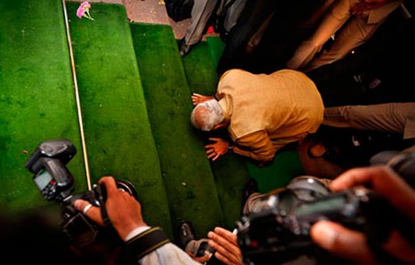 Narendra Modi bends down on his knees on the steps of the Indian parliament building as a sign of respect as he arrives for the BJP parliamentary party meeting in New Delhi