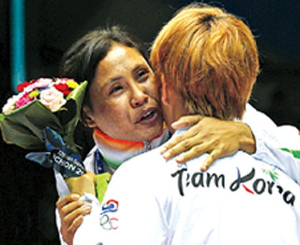 L.Sarita Devi gestures towards silver medalist South Korea's Park Ji-na as the latter tries to persuade Devi to accept her bronze medal