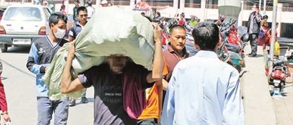 A migrant porter carries a bag of goods in the keithel area of Imphal 