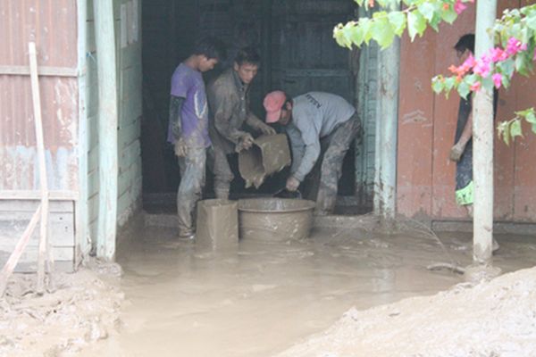 Volunteers removing mud and water from a flooded structure