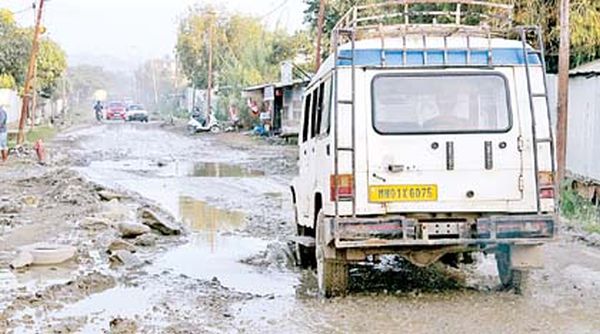 A vehicle makes its way through the dilapidated road stretch