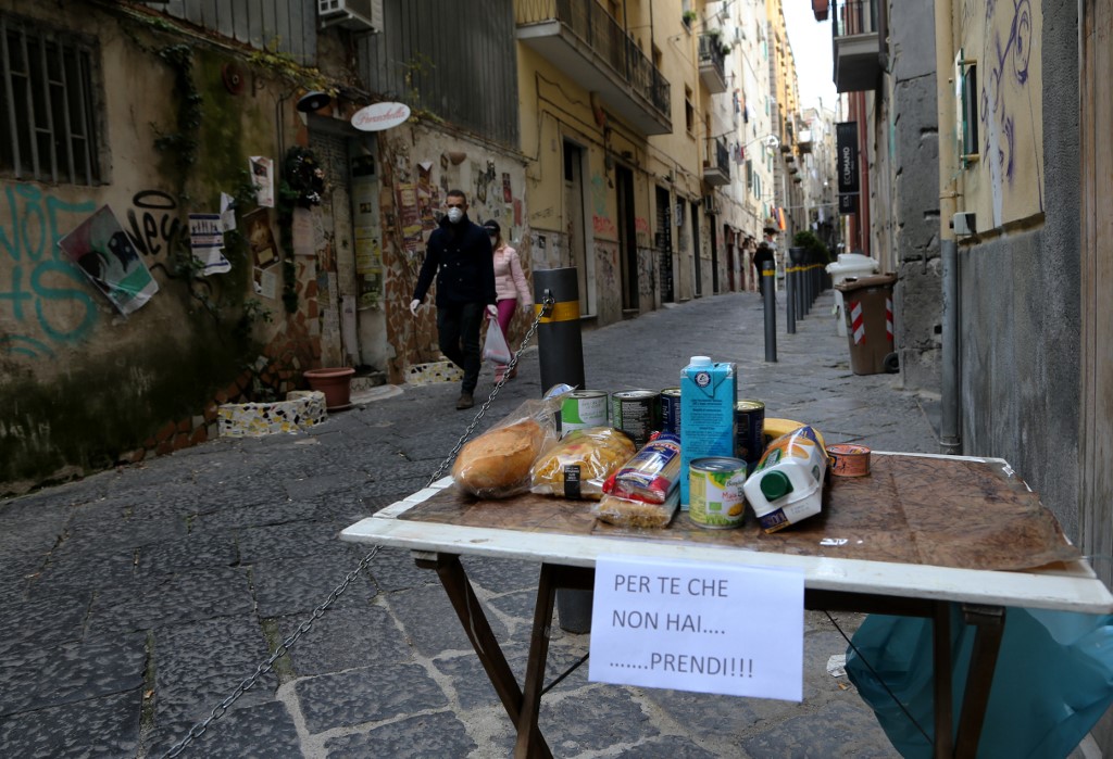  Free food on a table in a Naples street with a sign that reads 'For you who doesn't have much, take this!'. 